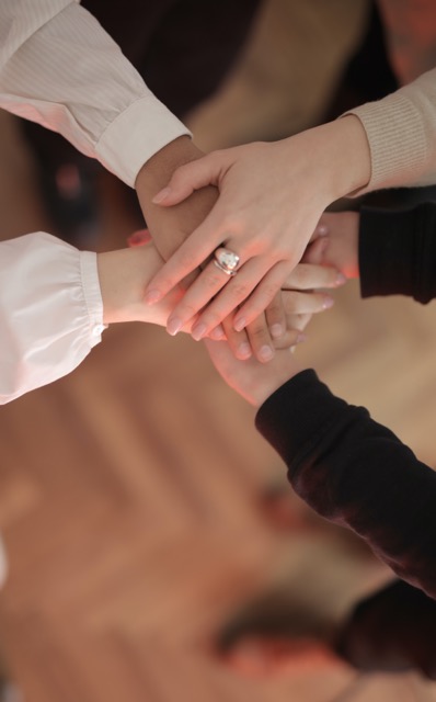 group of five people putting their hands together